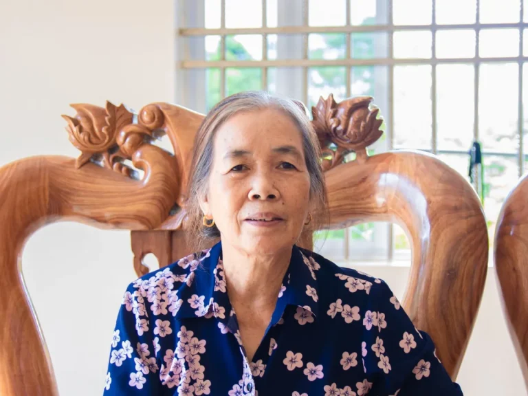 Cụ bà ngồi nghỉ trên ghế gỗ tại nhà