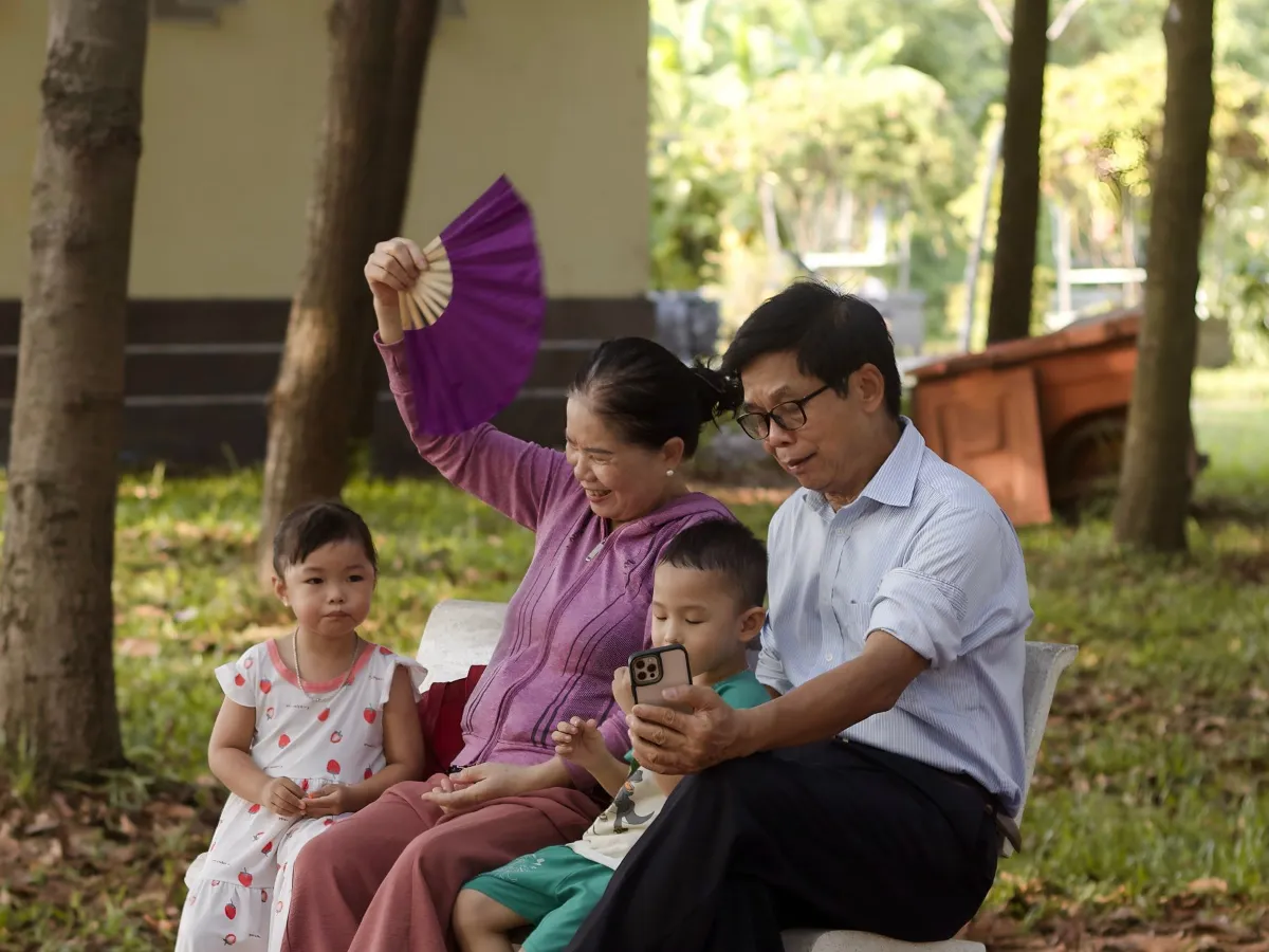 Gia đình ba thế hệ ngồi nghỉ trong công viên ở TP. Hồ Chí Minh